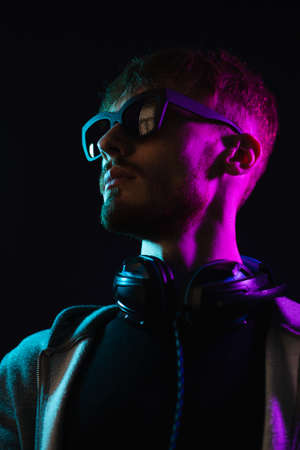 Neon portrait of a bearded man wearing headphones on the neck, wearing parka and mate sunglasses. Hacker portraitの写真素材