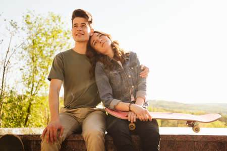 Caucasian skateboarder couple standing together prepare themselves to surf skate in the city Handsome man and beautiful woman enjoy skateboard exercising.の写真素材