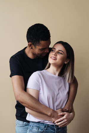 Love, new mixed race parents and family concept - very happy couple, celebrating the news of a pregnancy. Beige background.の写真素材