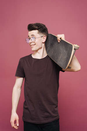 Portrait of young fashionable hipster man posing over pink background. Caucasian male holding...