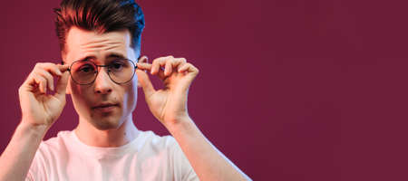 Isolated shot of young handsome male with glasses trendy hairdo, wears casual white t shirt, has...