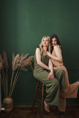 Family portrait, generations concept. Mom and adult daughter portrait on green wall backgroundの写真素材