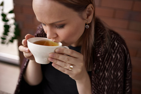 Close-up portrait of smiling woman drinking tea alone.の写真素材
