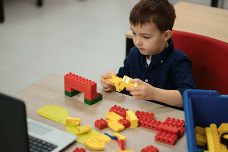 One kid choose parts of robotic electric toys for his age of four to build robots at robotics school lesson.の写真素材