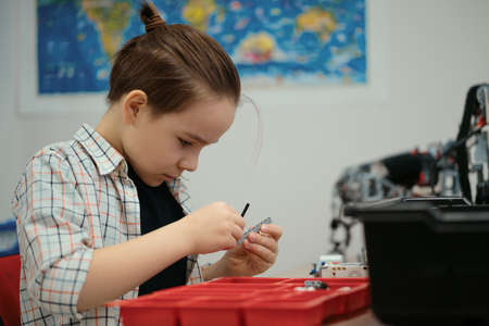 Boy Works on a Fully Functional Programable Robot for His School Robotics Club Project.の写真素材