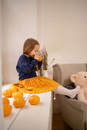 Little cute girl enjoy tangerines aroma sitting on the windowの写真素材