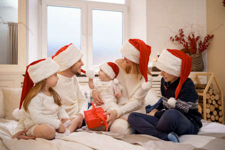 Merry Christmas and Happy New Year. Happy family are waiting Xmas Eve in Santa Claus hats while...
