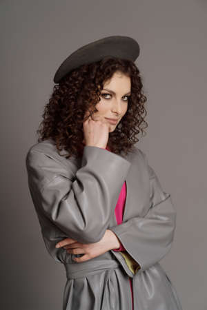 Studio shot of curly fashion model in bright pink clothes and leather jacket on gray background with copy spaceの写真素材
