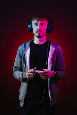 Portrait of gamer playing using a console. Gamer Wearing Headset Standing and holding white console...