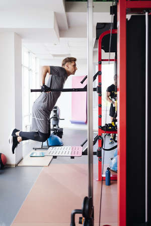 Athlete man in the gym doing elevations. Caucasian male training in the gym during the day