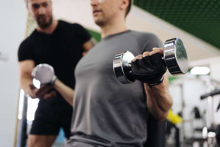 A personal trainer motivates the client to do push-ups in the gym. Personal workout hour with personal coachの写真素材