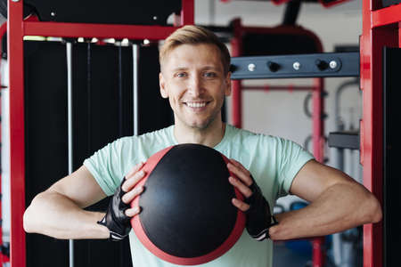 Athlete man working out with ball in the gym. Caucasian male training in the gym during the dayの写真素材