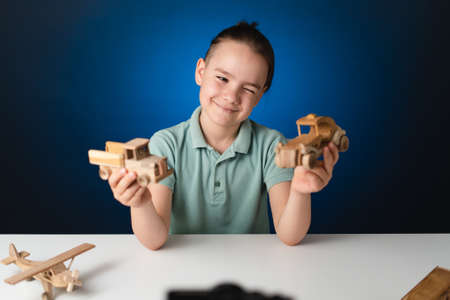 School boy playing, hands holding with wooden toys on white table, while staying at home on blue...