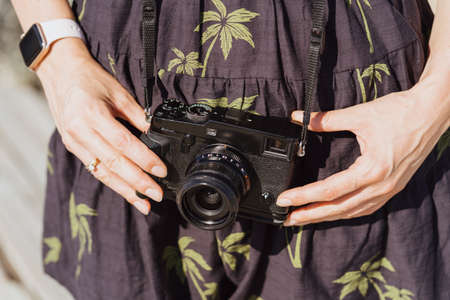 Tourist traveler photographer making pictures holding photo camera on dress with palms background, relax holidayの写真素材