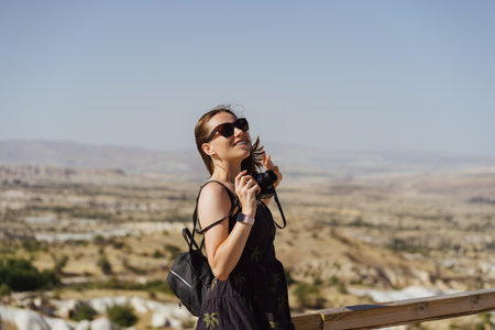 Young woman enjoying beauty of nature looking at mountains in Cappadocia. Adventure travel in...