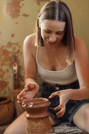 Woman hand potter making clay vase in pottery workshop studio. Process of creating ceramic vase. Handmade, hobby art and handicraft concept.の写真素材