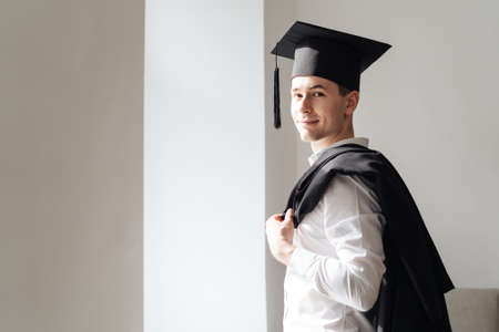 Education, graduation and people concept - happy male student with diploma at home showing his emotionsの写真素材
