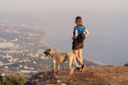 Woman successful hiking in mountains with a dog, motivation and inspiration in beautiful day