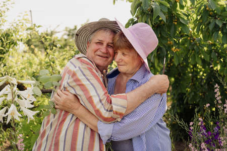 Lovely senior couple relaxing in the garden, hugging and kissing among trees and flowers. Happy life and healthy relationship. Beautiful familyの写真素材