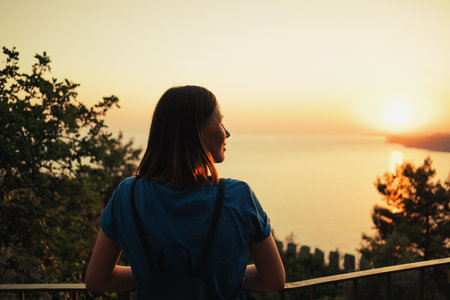 back view of women looking at beautiful abstract nature background with sea orange sunset on the coastlineの写真素材
