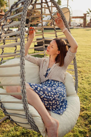 Woman relaxing on a resort outdoors, day dreaming and thinking, looking happy, smiling cheerfully.の写真素材