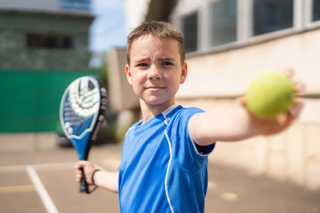 Sportive young boy with racquet playing padel in the open court outdoorsの写真素材