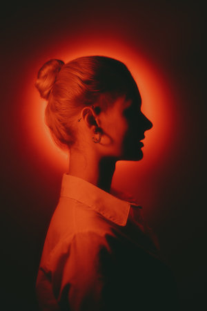 Woman profile portrait with glowing neon red circle on dark backgroundの写真素材