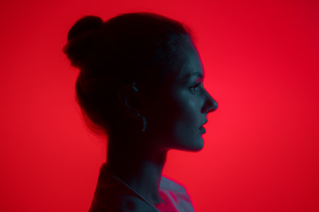 Dark woman profile portrait on red background with copy space. Lights play.の写真素材