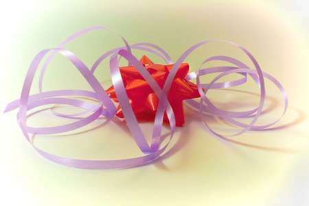 Red gift bow with lilac tapes on an abstract backgroundの写真素材