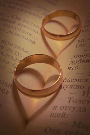 Shades in the form of hearts from two wedding rings lying on the book