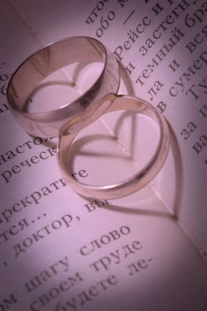 Shades in the form of hearts from two wedding rings lying on the bookの写真素材