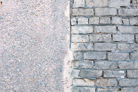 Two textures on one wall. The texture of brick and the texture of concrete plaster. Two textures in one image.の写真素材