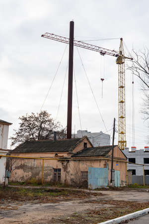 An old crumbling building, against the background of a new area under construction. A small boiler house is being destroyed, against the background of construction equipment and houses under constructの写真素材
