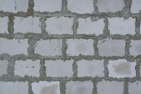 The background of the wall is made of gas silicate blocks bonded with cement mortar. Textured wall made of light blocks with cement mortar.の写真素材