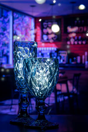 Glasses made of curly, blue glass shine, filled with light and create a desire to celebrate. Beautiful, transparent glasses shine, Merry Christmas and Happy New Year.の写真素材