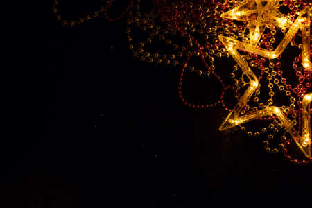 Golden stars and Christmas decorations form a copy space with a black background. Christmas tree toys create a desire to celebrate Christmas and New Year. A graphic resource for greeting cards.の写真素材