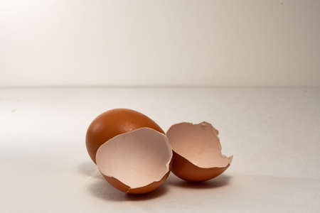 One whole chicken egg and two halves of the shell from a broken egg. Brown chicken eggs, one whole and one broken in two.の写真素材