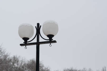 A street lamp, with round shades and lamps, sprinkled with snow. Winter park, strewn with snow, with lanterns and trees.の写真素材