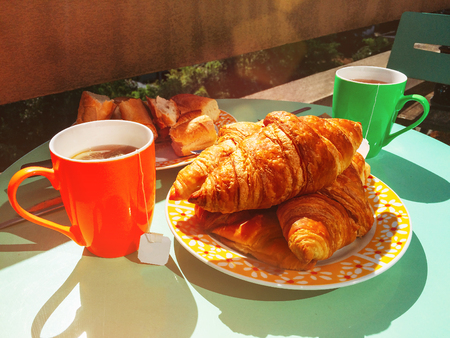 Delicious breakfast with tea on balcony, fresh croissantsの写真素材