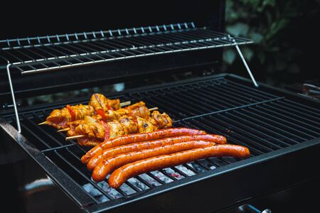 Meat skewers and sausages being grilled on a barbecue.の写真素材