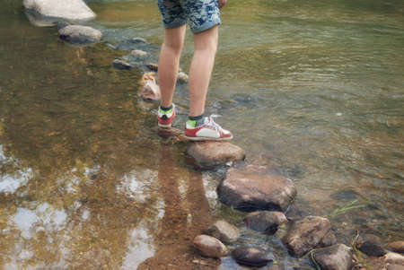 Crossing the rocks through the water flow of a mountain stream.の写真素材