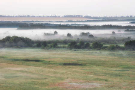 Dense fog over summer morning fields meadows and forests.