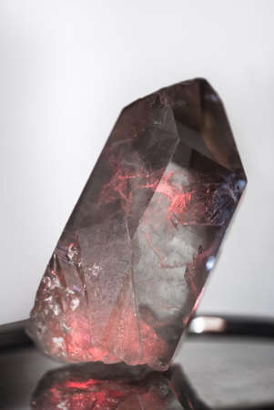 Large clear crystal of quartz chalcedony illuminated with red highlights white closeup.の写真素材