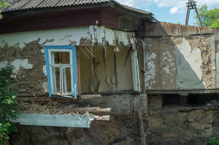 Ruined damaged building. Affected as a result of a natural disaster. A collapsed floor in the room of a private house, fragment of the wall and window. Destruction of the foundation by groundwater.の写真素材
