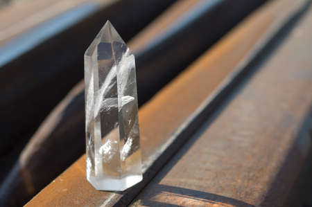 Large transparent mystical faceted crystal of white quartz on a rails on industrial background close-up. A wonderful mineral of the royal size for the designer.の写真素材