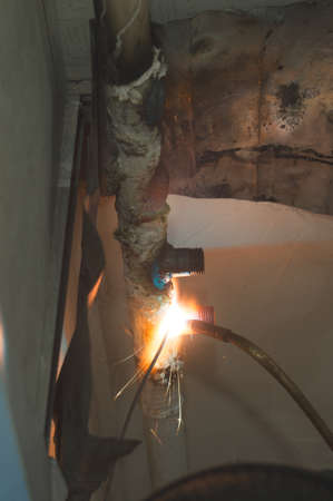 Welding work at home. The master welds the gas tubes with a gas torch, connects the molten hot metalの写真素材