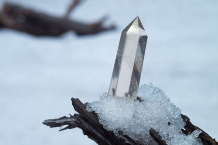 Perfect large shining crystal of transparent quartz in the sunlight on natural snow winter background close-upの写真素材