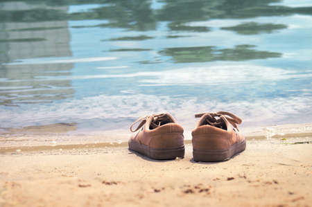 Footwear on the sand by the water of the lake. Shoes on the beach by the seaの写真素材