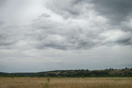 Clouds over scenic hills and meadows. Cloudy day in a picturesque summer valley.の写真素材