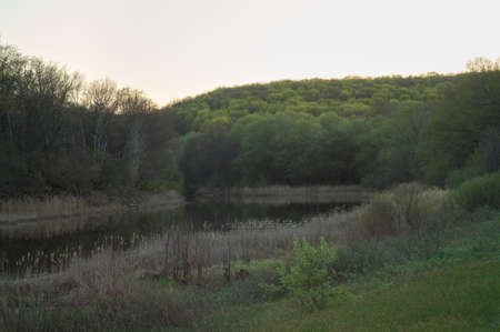 Picturesque spring evening landscape with hills, overgrown with verdant forest and a winding river at the foot, hiding on a turning.の写真素材